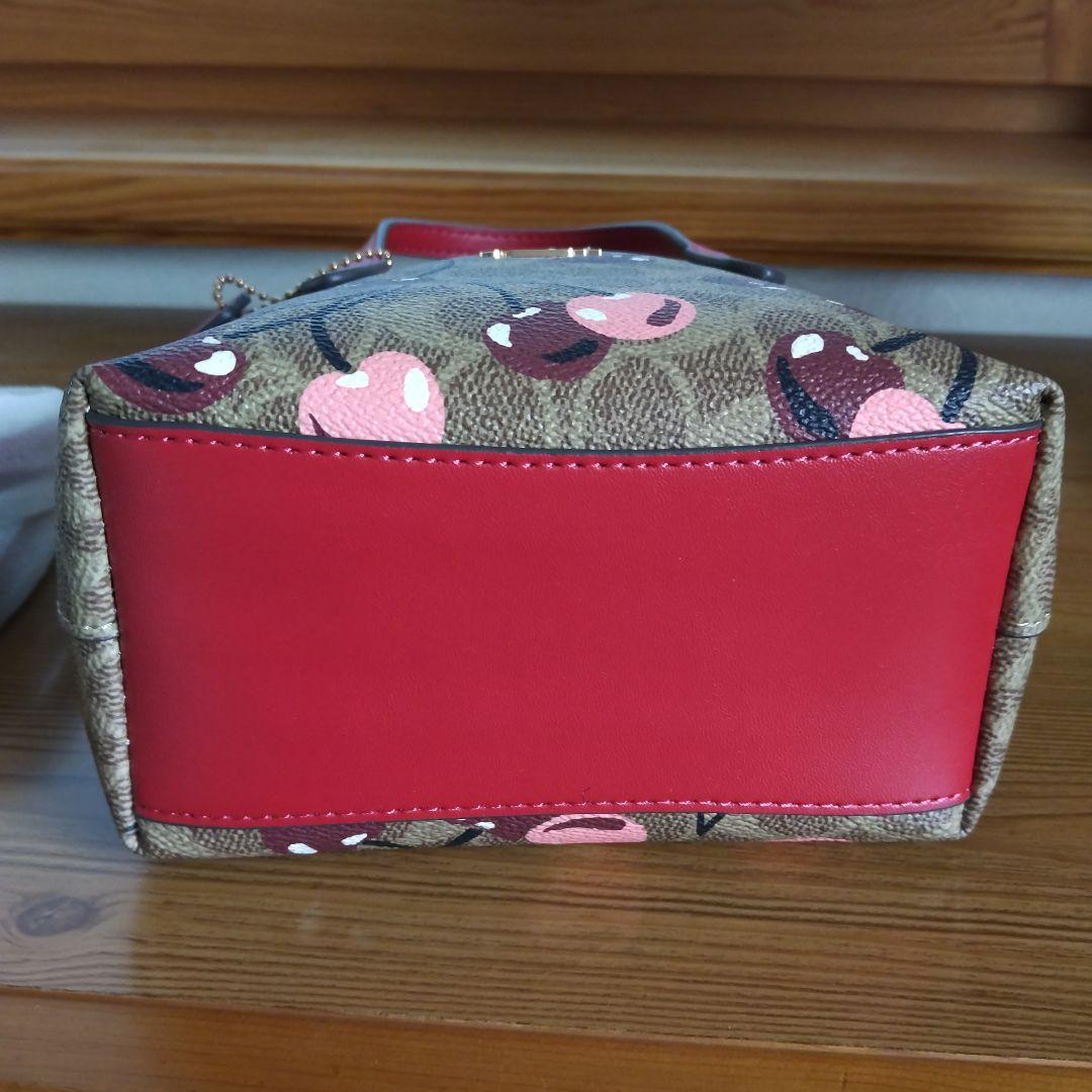 クリーム。COACHチェリー柄トートバッグ、ショルダーストラップ付き。